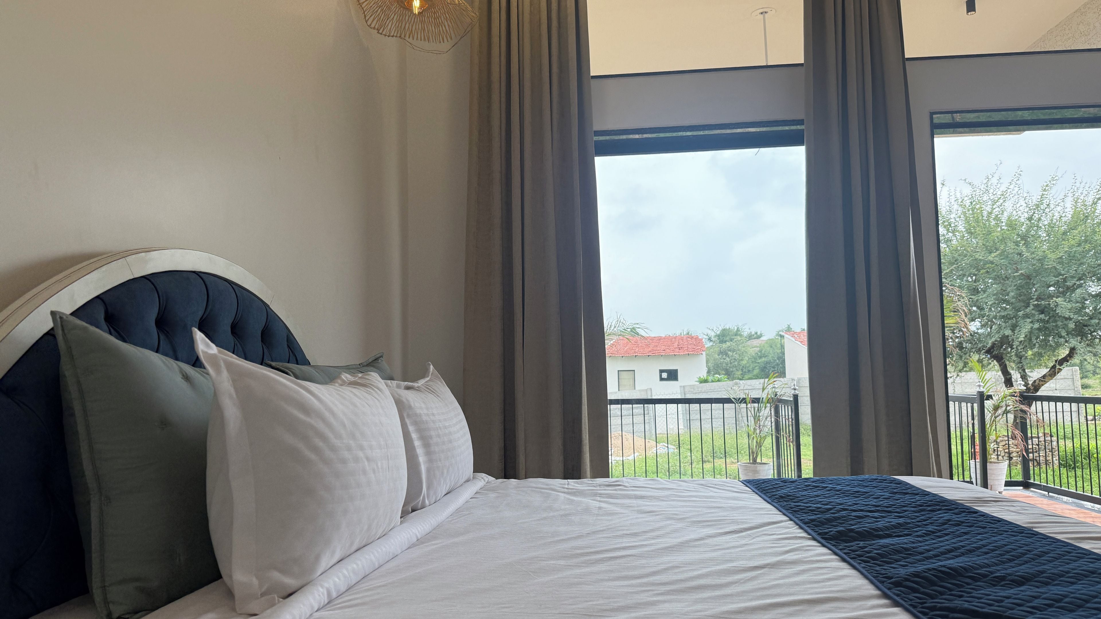 A bedroom with a large bed, a headboard, and a view of a balcony with a railing.