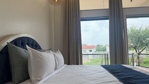 A bedroom with a large bed, a headboard, and a view of a balcony with a railing. -  Jaadooghar Aravalli Hideaway Jawai (Bali)