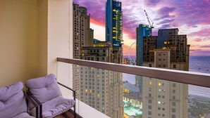 A balcony with a view of a cityscape at sunset, including high-rise buildings and a Ferris wheel.