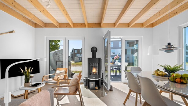 A modern living room with a fireplace, comfortable seating, and a dining area with fruit. - Haus Fabelhaft - Terrace, 2 Bathrooms, Fireplace, Infrared Sauna, SodaStream (Olpenitz)