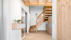 A modern interior with a wooden staircase, a built-in wardrobe, and a small plant on a wooden console. - Haus Fabelhaft - Terrace, 2 Bathrooms, Fireplace, Infrared Sauna, SodaStream (Olpenitz)