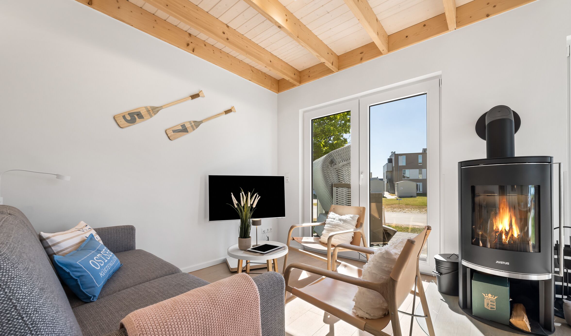 Una sala de estar moderna con chimenea, un sofá, un televisor y una ventana con vistas a edificios.