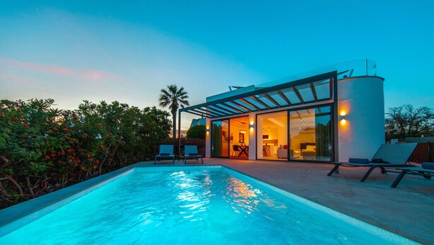 A modern house with a swimming pool, lounge chairs, and a glass-enclosed patio area. - Villa Farol Boutique (Lagoa)