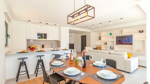 A modern kitchen with a dining area, a living room, and a TV. - Villa Farol Boutique (Lagoa)
