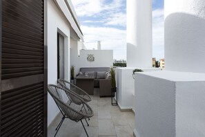 A balcony with wicker furniture, a sofa, and a small table.