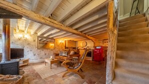 Un intérieur rustique avec des poutres apparentes, une cheminée en pierre, une chaise en bois et un escalier.