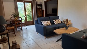 A living room with a sofa, a wooden coffee table, and a dining area with chairs and a table.