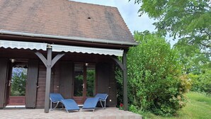 A wooden building with a tiled roof and a covered porch with two lounge chairs.