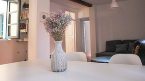 A dining table with a white vase containing flowers, a bookshelf, a door, and a sofa in the background. - El 8 de Serranos_bottom_house with garage (León)