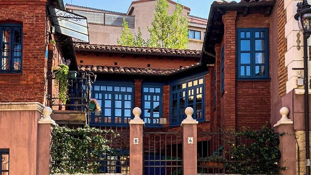 A traditional building with a tiled roof, a gated entrance, and a small balcony with plants. - El 8 de Serranos_bottom_house with garage (León)
