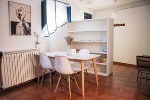 A dining area with a white table, four chairs, a vase with flowers, a radiator, a bookshelf, and a painting on the wall. - El 8 de Serranos_bottom_house with garage (León)
