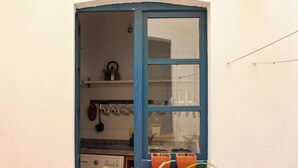 A small kitchen with a washing machine, a window with blue trim, and potted plants on the windowsill. - El 8 de Serranos_bottom_house with garage (León)