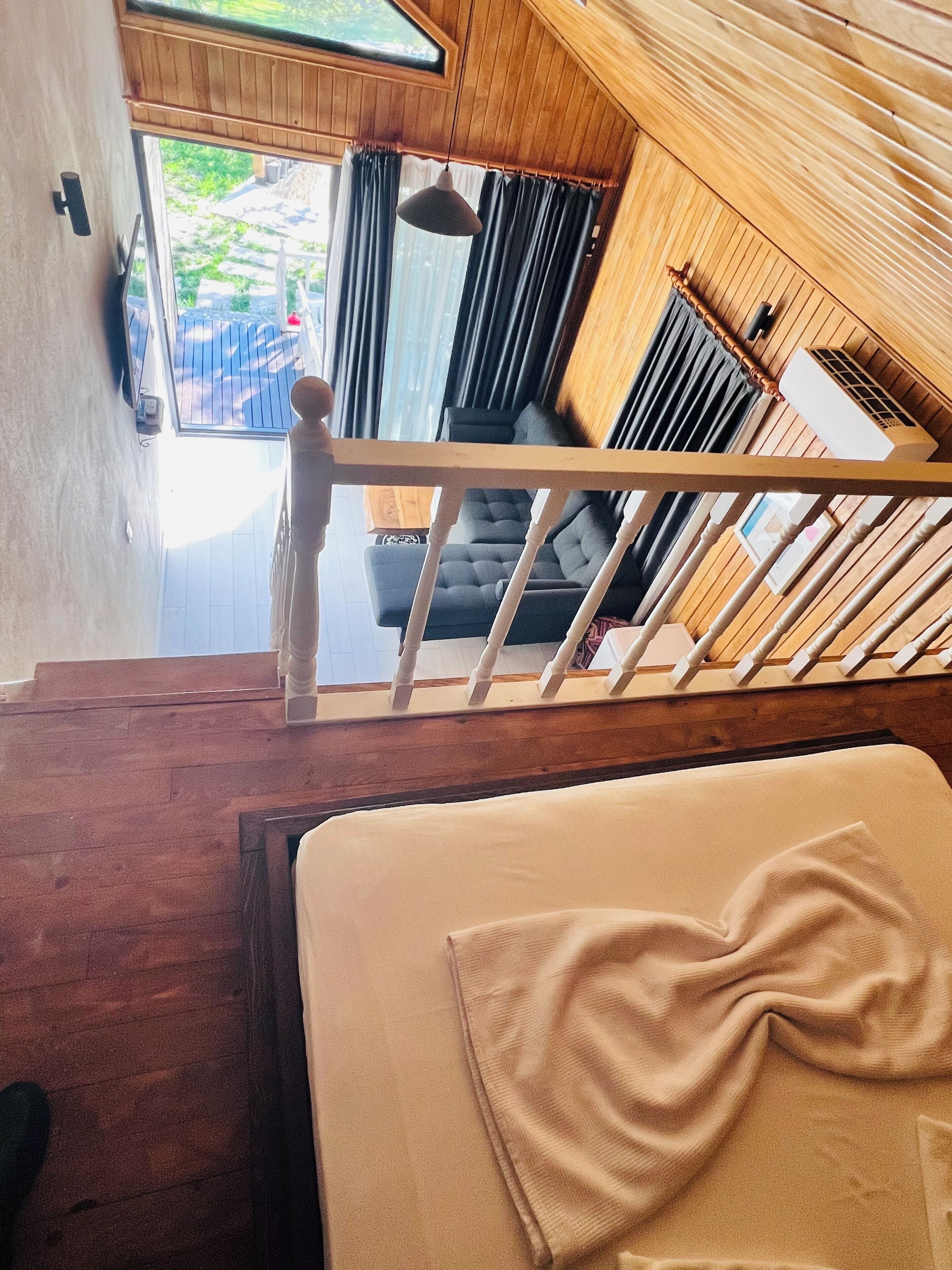 Eine Holztreppe führt zu einem Balkon mit Blick ins Freie.