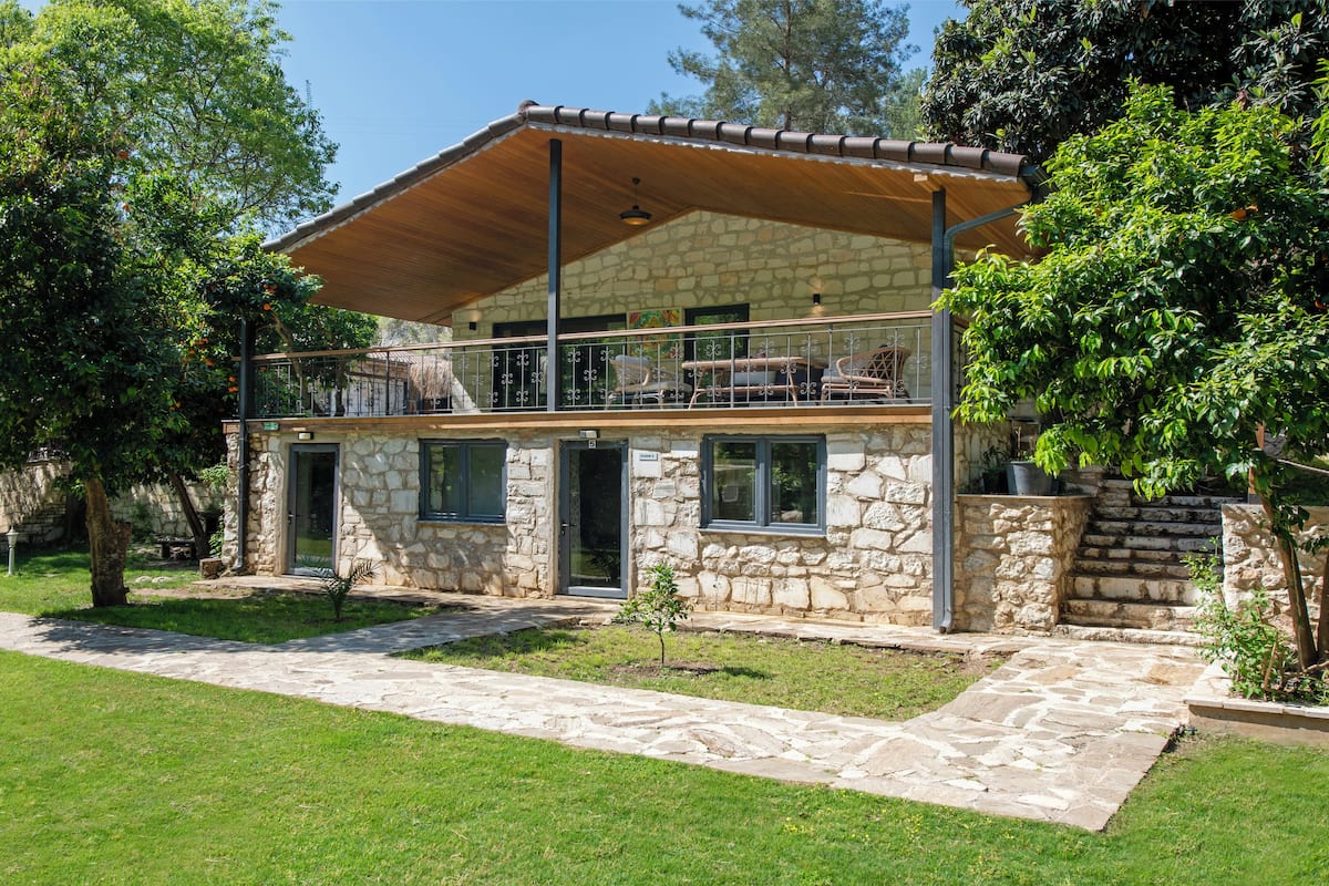 A stone house with a covered balcony and a stone pathway leading to the entrance.