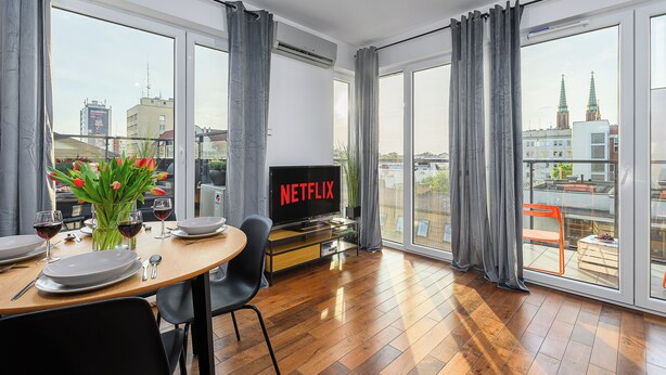 Sala de estar moderna com área de refeições, janelas amplas e vista para a paisagem urbana.