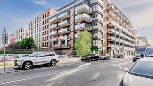 Um edifício residencial com várias andares, varandas e um estacionamento em frente.