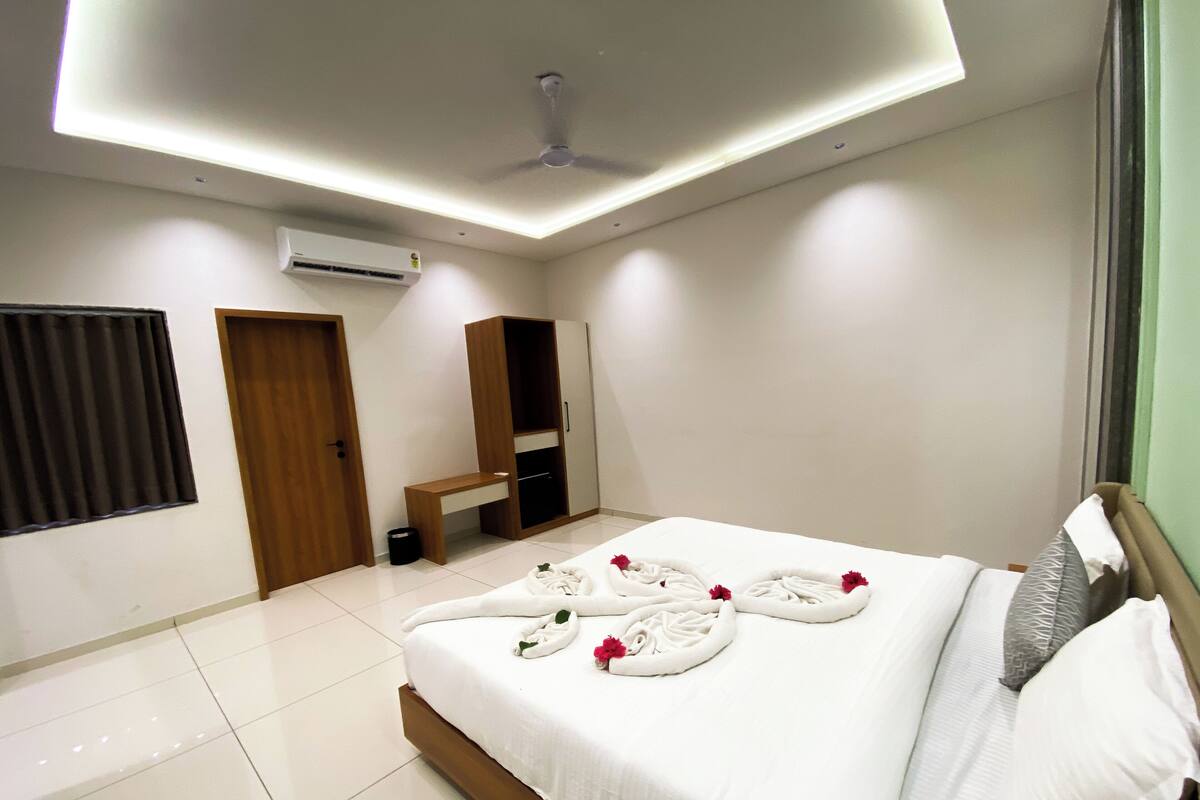 A modern hotel room with a neatly made bed, a wooden bench, and a wardrobe.