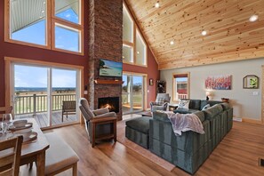 Un salón amplio con chimenea, ventanas grandes y un techo alto.