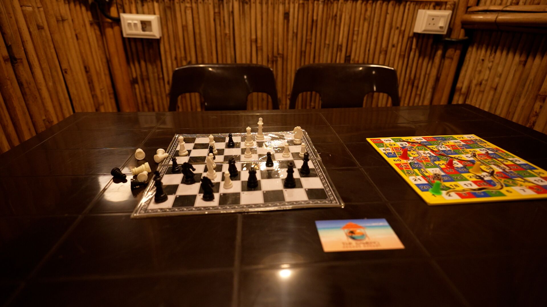 Ein Tisch mit Schachbrett, Spielbrett, zwei Stühlen und einer Spielkarte.