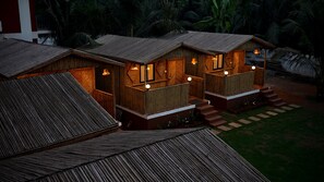 Un bungalow in legno con un balcone, scale che conducono all'ingresso e un esterno ben illuminato.