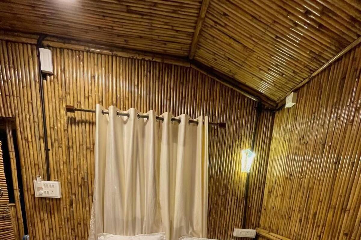 Una habitación con cama, paredes de madera y una cortina.
