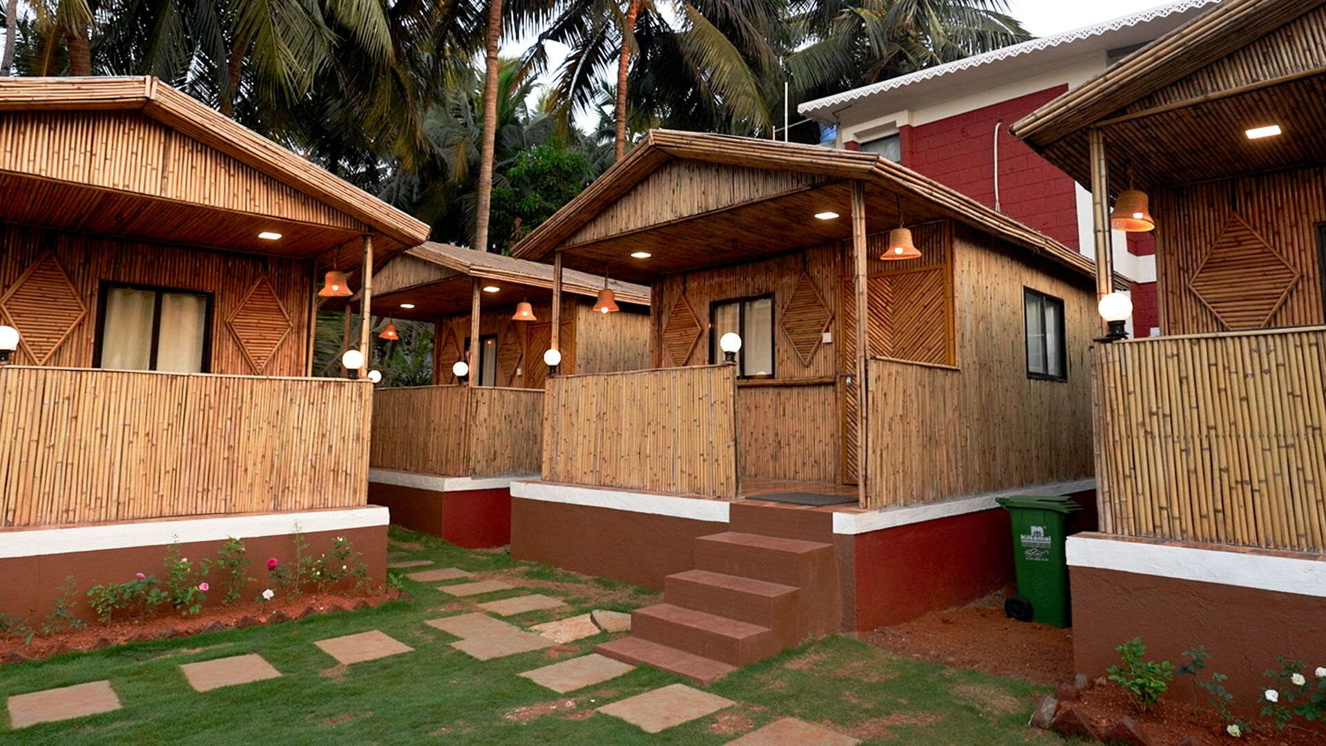 A row of wooden cabins with a covered patio area, steps leading to the entrance, and a garden with stepping stones.