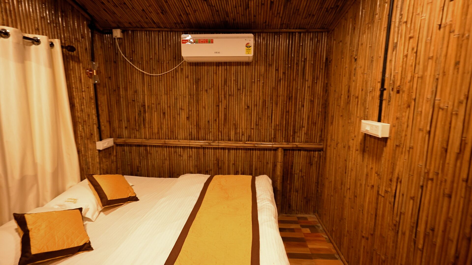 A room with a bed, a wall-mounted air conditioner, and a wooden floor.