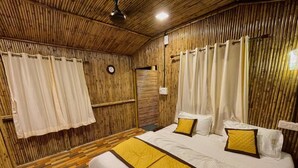 Una habitación con techo de madera, cama con ropa de cama blanca y detalles en amarillo, y un reloj en la pared.