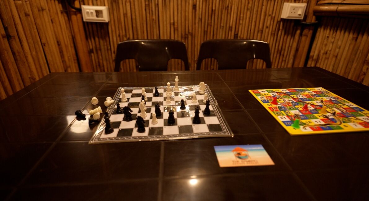 A chessboard on a table in a room with wooden walls and two chairs.