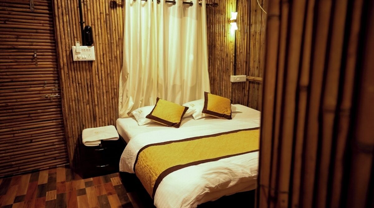 A hotel room with a bed, a bedside table, a lamp, and a curtain.