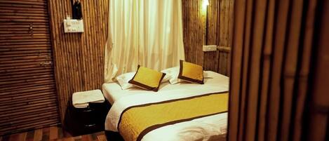 A hotel room with a bed, a bedside table, a lamp, and a curtain.