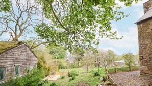 Ein rustikales Holzhaus mit Steinwand, ein Garten mit Holzzaun und einem klaren Himmel.