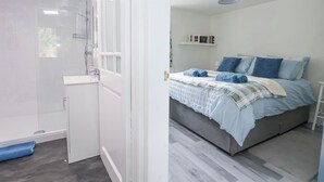 Ein modernes Badezimmer mit Duschkabine aus Glas und separatem Waschbeckenbereich.