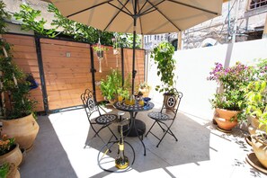 An outdoor patio with a round table, two chairs, a hanging planter, and a hookah. - PORT CITY HAIFA - Urban Oasis (Haifa)