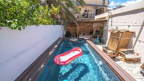 Une piscine rectangulaire avec un toboggan gonflable rouge et un ballon multicolore.