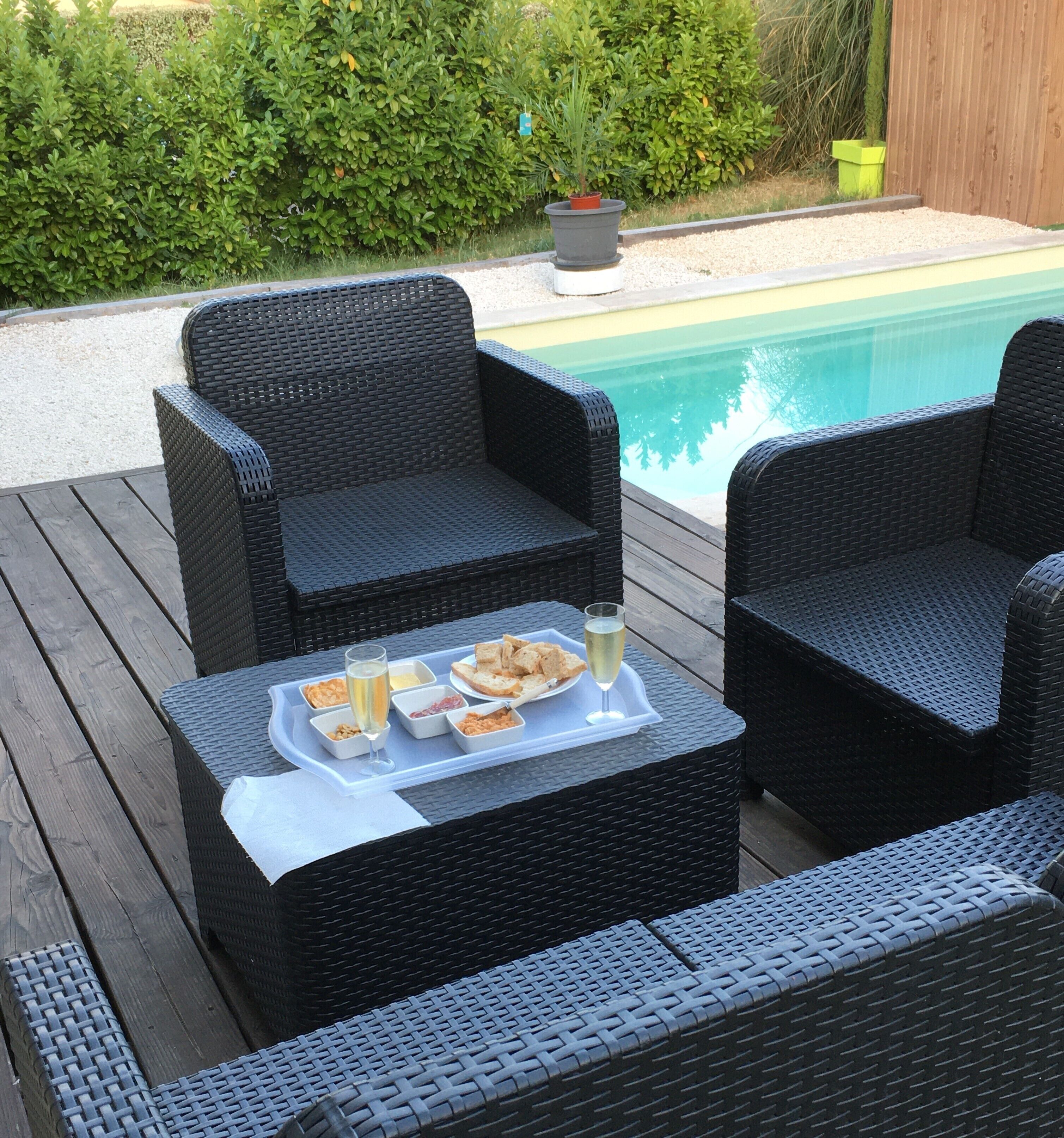 A deck with wicker furniture and a tray of food and drinks.