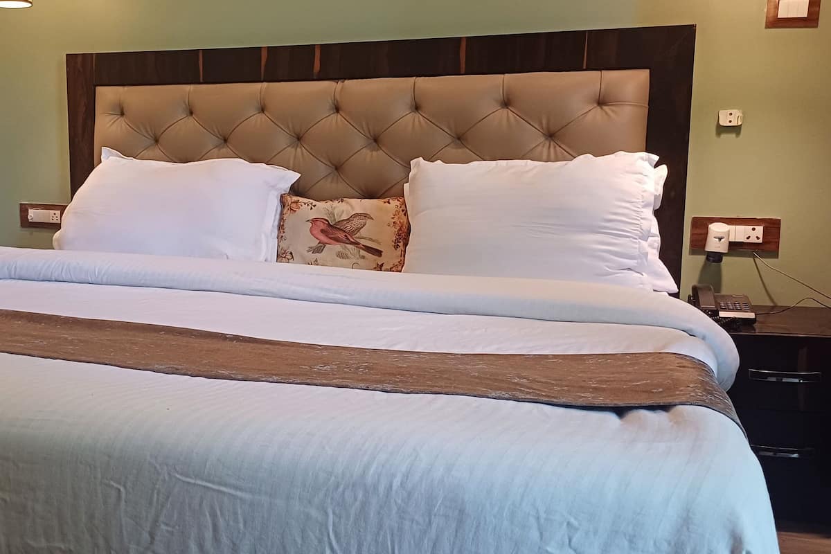 A neatly made bed with a tufted headboard, white bedding, and a decorative pillow.
