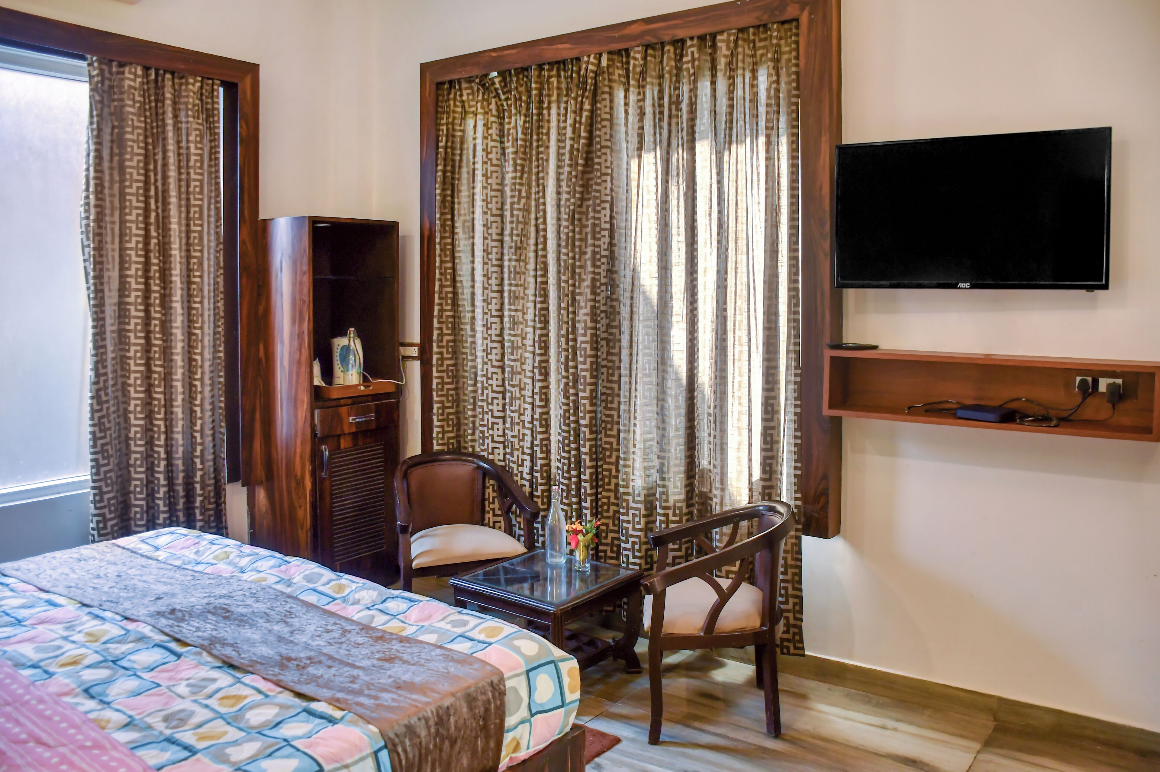 A hotel room with a bed, a desk with a chair, a television, and curtains.