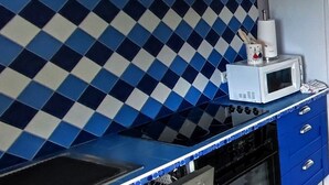 A kitchen with blue and white checkered backsplash, a microwave, a stove, and a dishwasher.