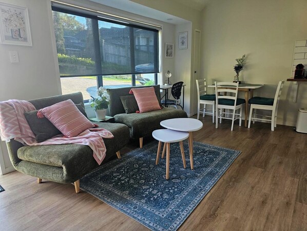 A cozy living room with a sectional sofa, a small round table, and a dining area with chairs.