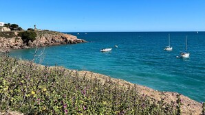 A coastal scene with rocky cliffs, clear blue sea, and boats. - Charming 2-room in Sète with private parking, canal view (Sète)