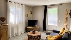 Un salon moderne comprenant un canapé, une table basse ronde en bois, un téléviseur et un meuble.