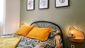 Une chambre à coucher avec un lit, une table de chevet avec une lampe et trois tableaux encadrés accrochés au mur.