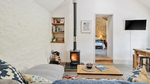 Ein gemütliches Wohnzimmer mit Kamin, Bücherregal, Fernseher und einer bequemen Sitzecke.