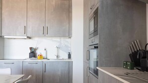 Une cuisine moderne avec des meubles gris, un plan de travail en marbre et des appareils électroménagers en acier inoxydable.