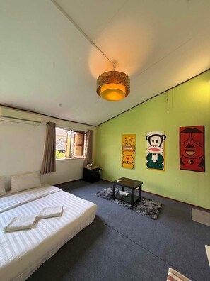 A room with a bed, a table, and a wall with three artworks. - Baan Natee (Chiang Khan)