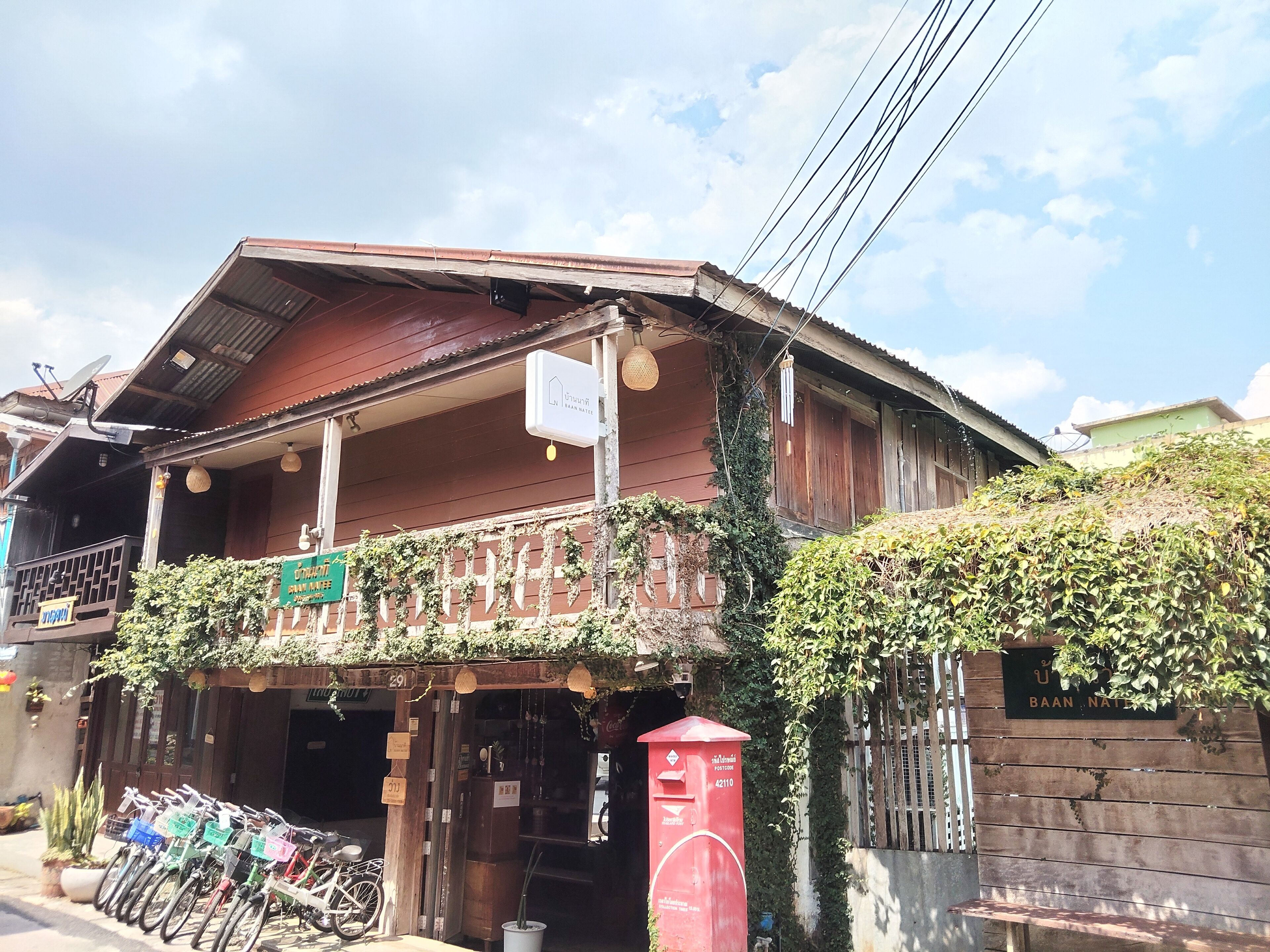 A traditional wooden building with a balcony, a post office, and bicycles parked outside.