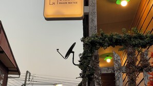 Ein Schild mit thailändischem Text und einem Haus-Symbol, das das Hotel "BAAN NATEE" kennzeichnet.