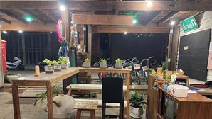 Ein gemütlicher Innenraum mit Holzmöbeln, einem Fernseher und verschiedenen Blumentöpfen.