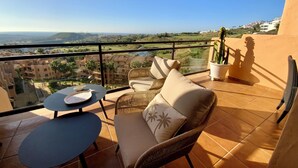 A balcony with wicker furniture, a table, and potted plants.